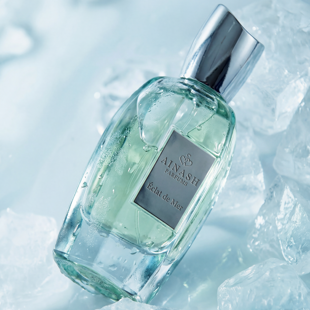 Perfume bottle labeled 'Aimash' on a light blue background with ice cubes.